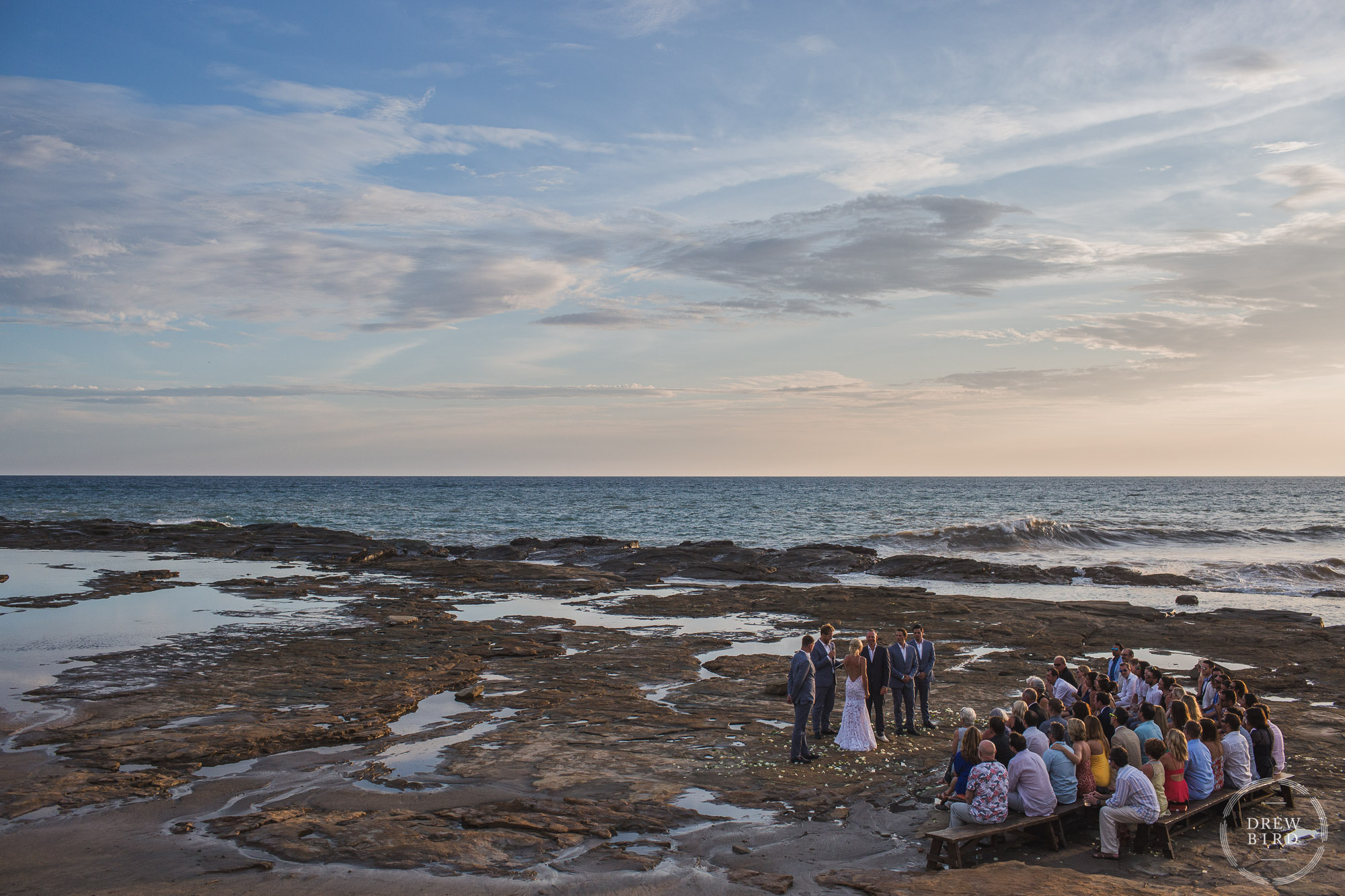 Intimate wedding ceremony on tidal rocks on the beach at sunset. Rancho Santana Nicaragua destination wedding photographer Drew Bird.