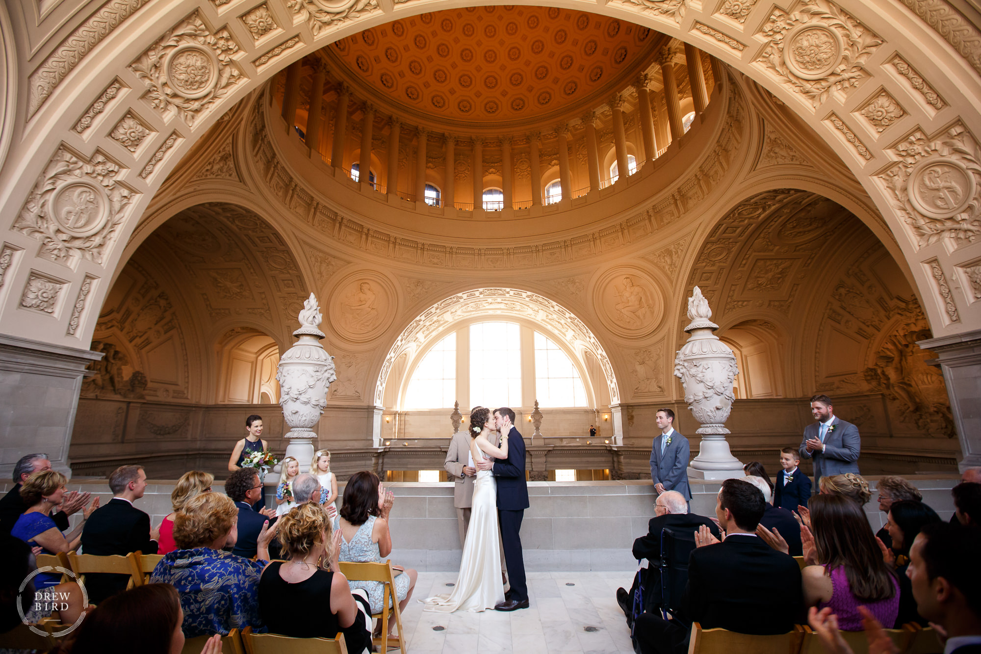 Bride and groom kiss during ceremony on fourth floor gallery at a San Francisco City Hall wedding.