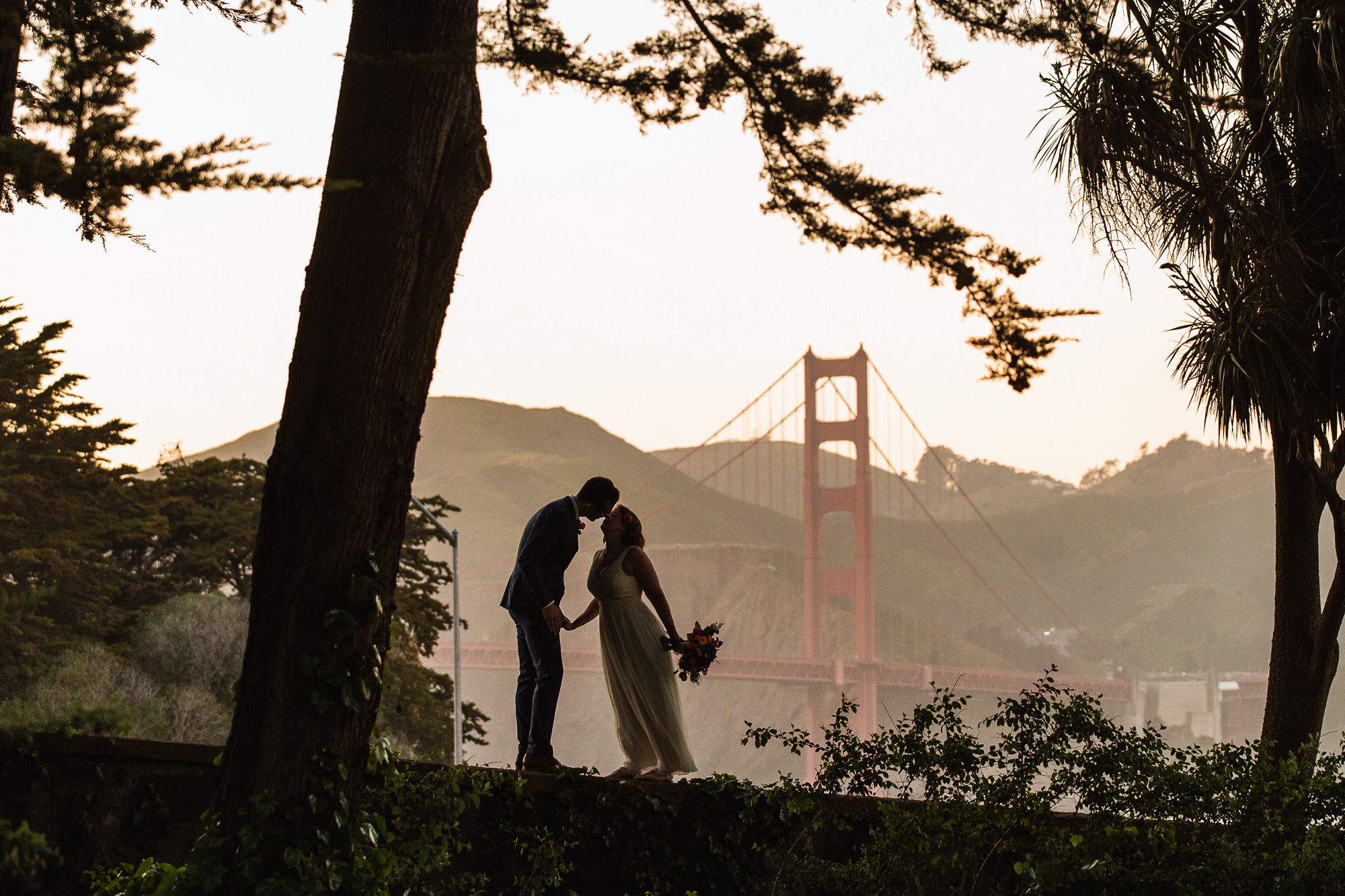 Bride and groom wedding couple silhouetted at sunset at The Golden Gate Club a wedding venue in the Presidio of San Francisco.