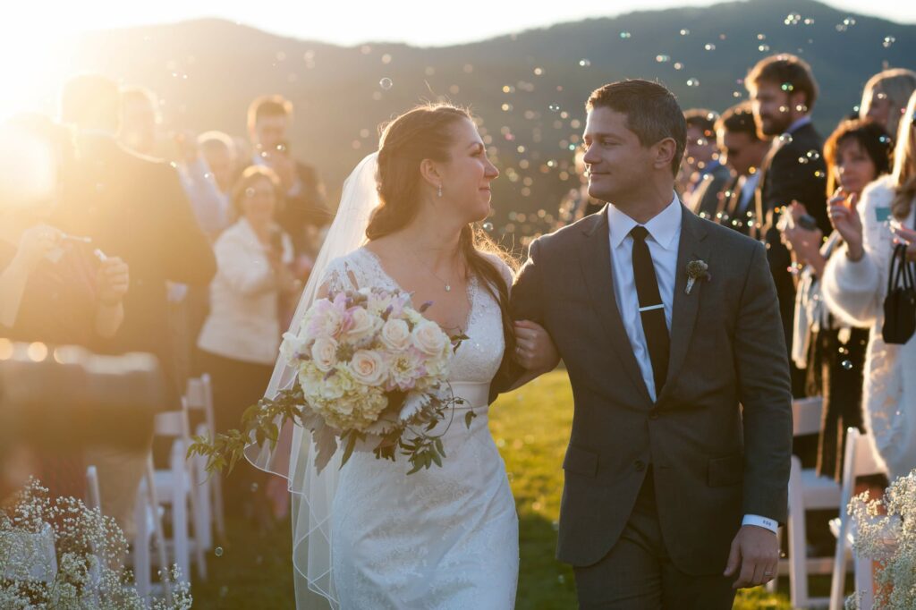 bride and groom walk up the aisle smiling at each other after exchanging vows