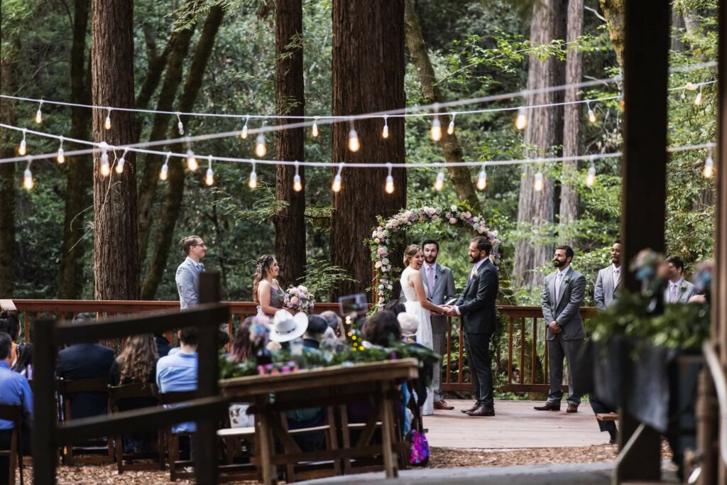 bride and groom exchange vows at their Redwood forest wedding whilst guests watch
